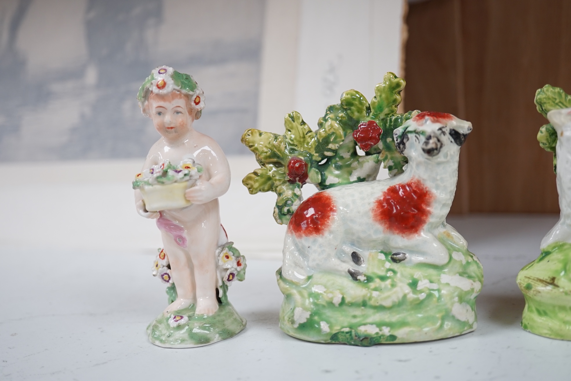 A pair of early 19th century pearlware models of sheep, an English porcelain ‘sheep’ ring tree and a Derby figure of a cherub, tallest 10 cm. Condition - ring tree restored the others fair to good